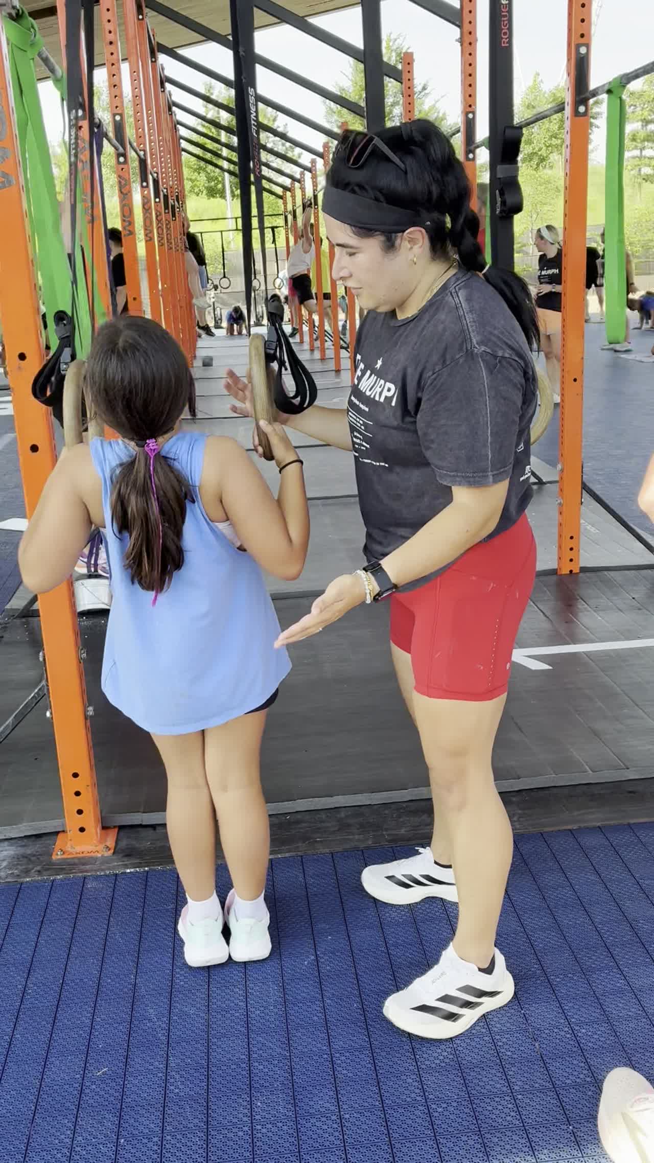A coach guides a young girl on the rig at Arize Training Club.